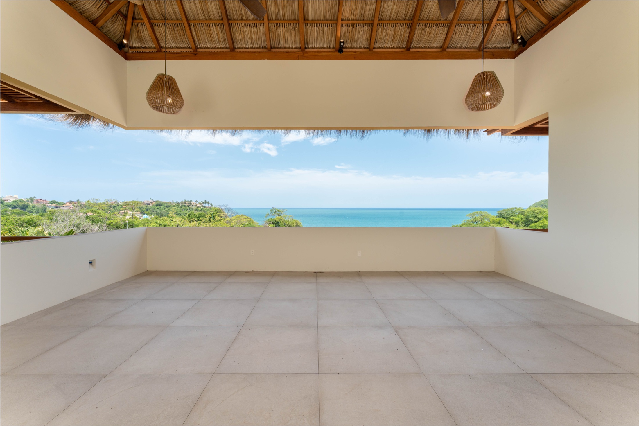 Sala bajo techo de palapa abierta a una vista panorámica del mar en una residencia ROCA